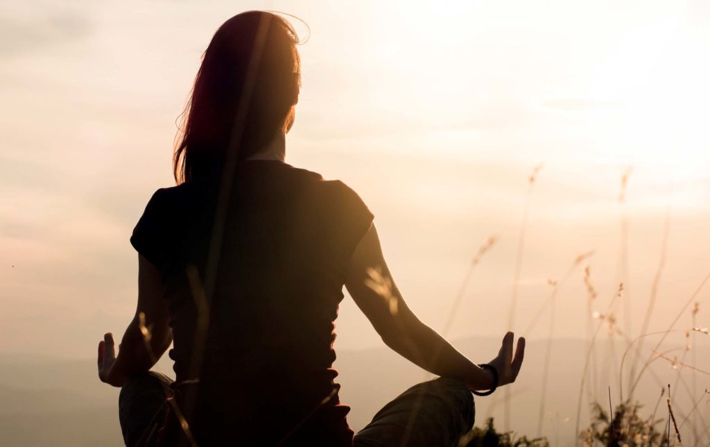 Frau macht Yoga im Sonnenuntergang